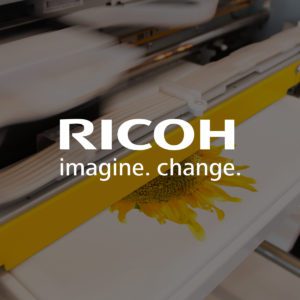 Vibrant printout of a sunflower coming out of an industry printer in motion in the background with Ricoh logo