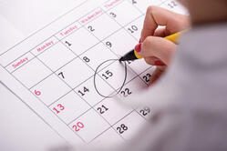 A female employee circling the date fifteenth on the calendar