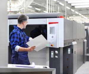 A male factory professional looking at a printout from an industrial scale printer