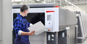 A male factory professional looking at a printout from an industrial scale printer