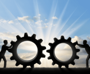shadows of two men pushing huge gears towards each other against a bright cloudy sky