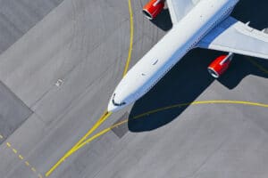 Aerial view of airplane with red engines taxiing to the runway before takeoff